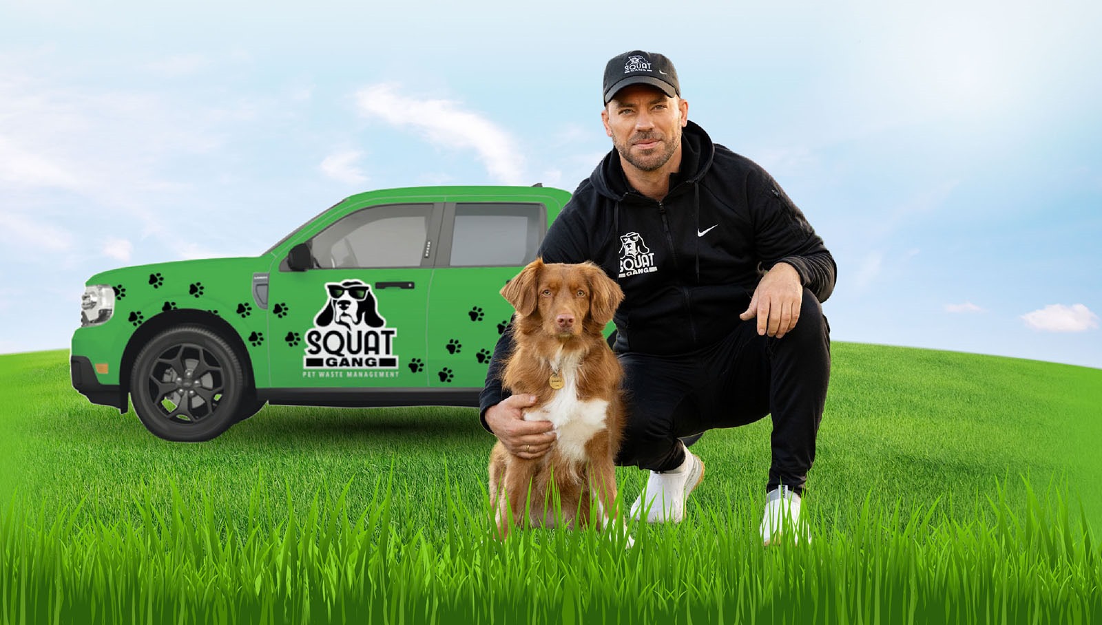 Man in black attire kneels beside a brown dog in front of a green pet waste management truck.